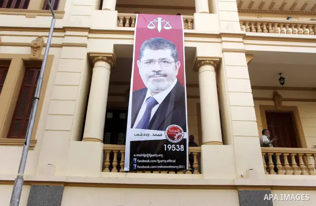 Egyptians walk under a banner of the Muslim Brotherhood's presidential candidate Mohammed Mursi in Cairo on May 25, 2012. Egypt looked set for a run-off presidential vote pitting Mursi against Mubarak-era minister Ahmed...