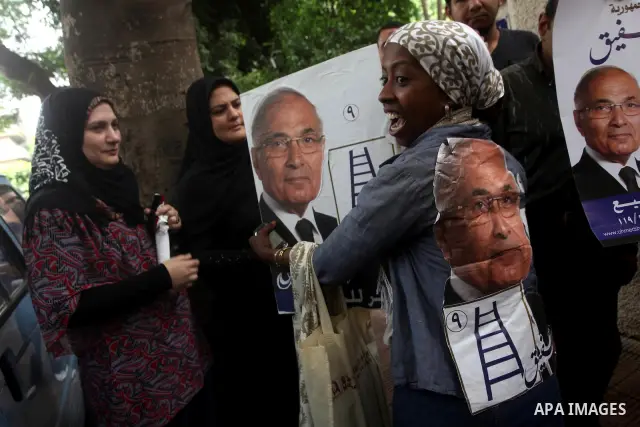Supporters of Egyptian presidential candidate and former prime minister Ahmed Shafiq holds his poster during a press conference in Cairo on May 26, 2012. Shafiq, ousted leader Hosni Mubarak's ex-premier who is set to fac...