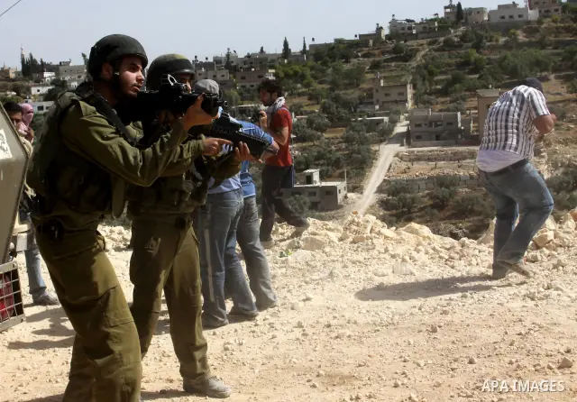 Palestinian protesters run for cover as Israeli forces fire in the air to disperse the crowd during clashes that followed the setting on fire of fields of grain and olive trees by hardline settlers from the Jewish settle...