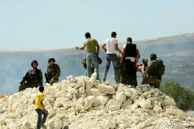 Palestinian protesters run for cover as Israeli forces fire in the air to disperse the crowd during clashes that followed the setting on fire of fields of grain and olive trees by hardline settlers from the Jewish settle...