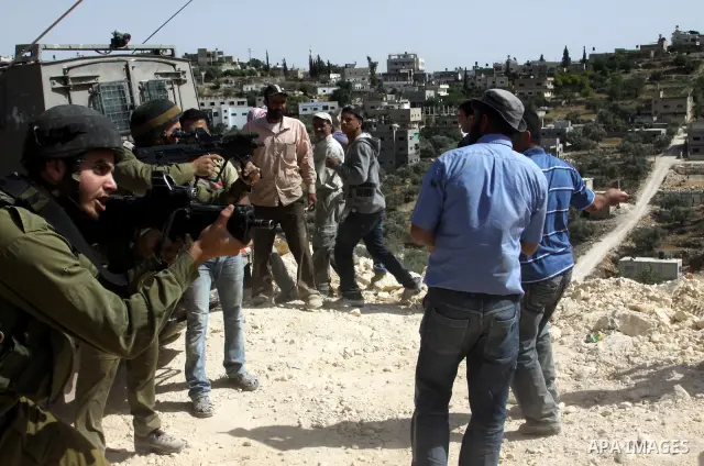 Palestinian protesters run for cover as Israeli forces fire in the air to disperse the crowd during clashes that followed the setting on fire of fields of grain and olive trees by hardline settlers from the Jewish settle...