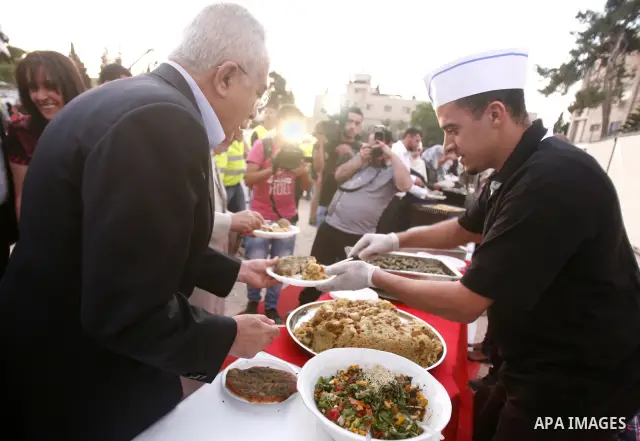 Palestinian Prime Minister Salam Fayad fills his plate with a local salad dish after receiving the certificate for the longest buffet of natural and organic food which registered a new guinness world record, on May 26, 2...