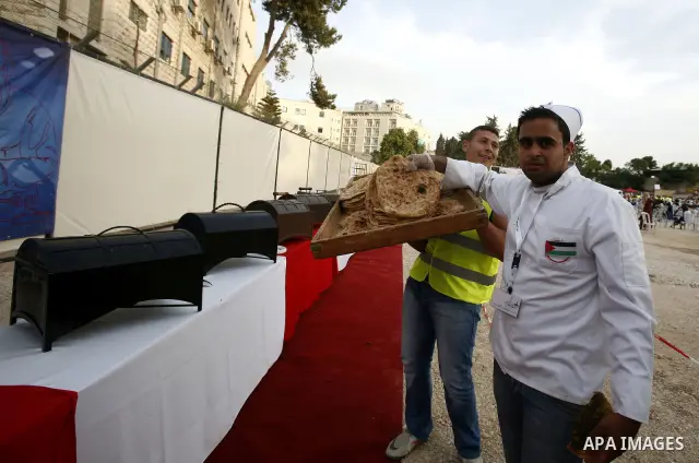 A chef carries a tray of leavened bread garnished with thyme as he and others prepare the longest buffet of natural and organic food which registered a new Guinness world record, on May 26, 2012 in Arab east jerusalem. T...