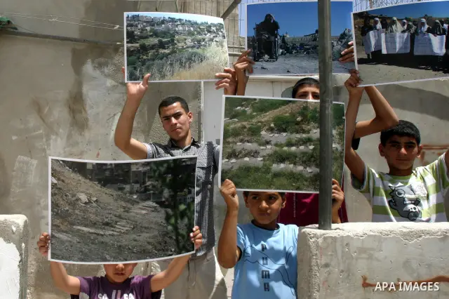 Palestinian children hold pictures of the judaized land during a press conference discusses the issue of judaizing Jerusalem and the alleged Jewish graves in Valley Rababa, in Silwan Jerusalem's old city, In Jerusalem on...