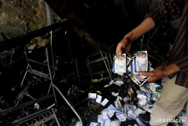 A man shows flyers of presidential candidate Ahmed Shafiq at the scene of the burnt campaign headquarters of Shafiq in Cairo May 29, 2012. A group of Egyptian protesters set fire to the headquarters on Monday, the state...