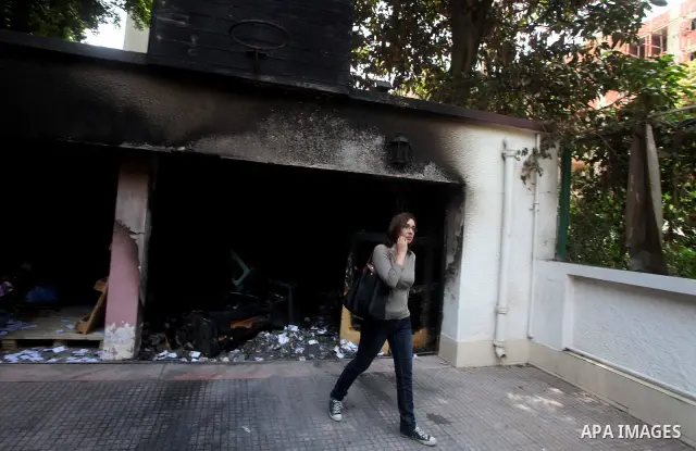 Egyptian woman walks in front of the burnt campaign headquarters of candidate and former prime minister Ahmed Shafiq in Cairo May 29, 2012. A group of Egyptian protesters set fire to the headquarters on Monday, the state...
