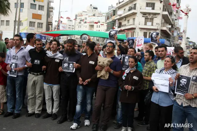 Palestinian protesters hold pictures of prisoners, as they bang pots with kitchen utensils during a demonstration in the West Bank city of Ramallah on May 29, 2012 in support of Palestinian prisoners Mahmoud al-Sarsak an...