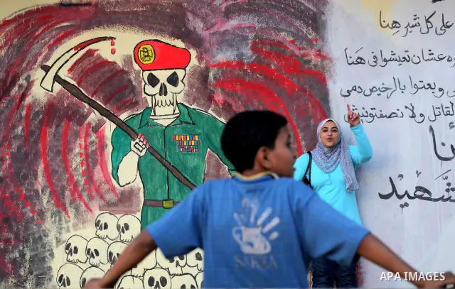 Egyptians walk in front of a wall sprayed graffiti at Tahrir Square in Cairo May 30, 2012. An arson attack on the headquarters of one of the two candidates in Egypt's presidential election has marred campaigning for the...