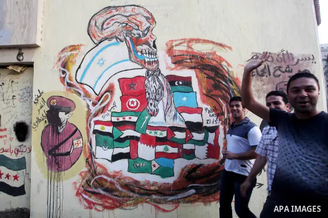 Egyptians walk in front of a wall sprayed graffiti at Tahrir Square in Cairo May 30, 2012. An arson attack on the headquarters of one of the two candidates in Egypt's presidential election has marred campaigning for the...