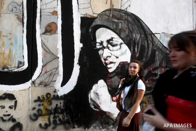 Egyptians walk in front of a wall sprayed graffiti at Tahrir Square in Cairo May 30, 2012. An arson attack on the headquarters of one of the two candidates in Egypt's presidential election has marred campaigning for the...
