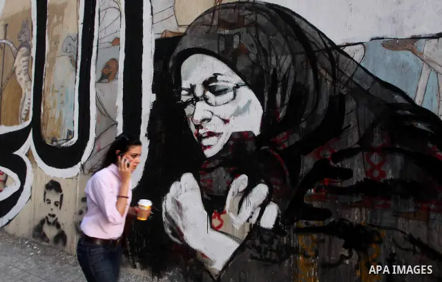 Egyptians walk in front of a wall sprayed graffiti at Tahrir Square in Cairo May 30, 2012. An arson attack on the headquarters of one of the two candidates in Egypt's presidential election has marred campaigning for the...