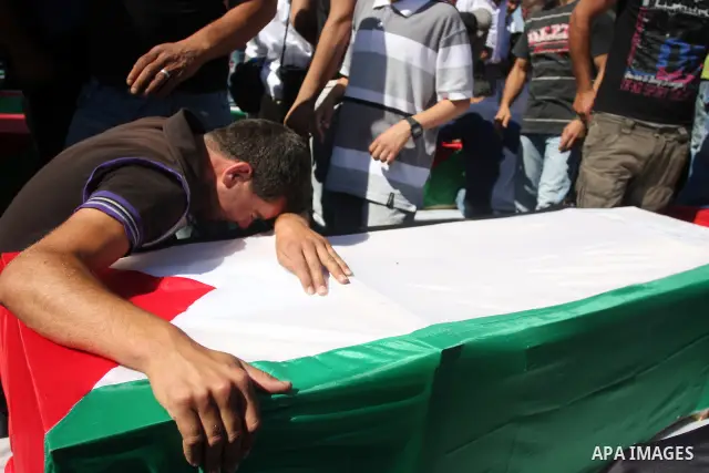 Palestinian man mourn over a flag-draped coffin prior to the funeral of 91 Palestinians whose remains were returned by Israel at the Palestinian leadership headquarters in the West Bank city of Ramallah on May 31, 2012....