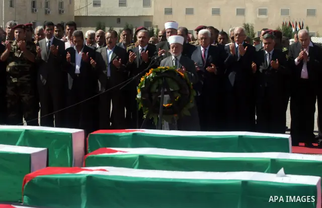Palestinians pray over flag-draped coffins during the funeral of 91 Palestinians whose remains were returned by Israel at the Palestinian leadership headquarters in the West Bank city of Ramallah on May 31, 2012. Israel...