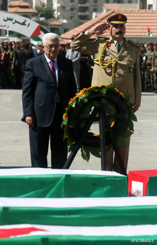 Palestinian President Mahmoud Abbas (C) prays over flag-draped coffins during the funeral of 91 Palestinians whose remains were returned by Israel at the Palestinian leadership headquarters in the West Bank city of Ramal...