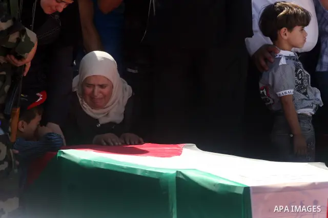 Palestinian woman mourn over a flag-draped coffin prior to the funeral of 91 Palestinians whose remains were returned by Israel at the Palestinian leadership headquarters in the West Bank city of Ramallah on May 31, 2012...