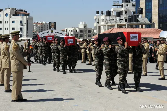 Members of the Palestinian security forces carry flag-covered coffins containing the remains of Palestinian militants during an official ceremony in the West Bank city of Ramallah May 31, 2012. The remains of 91 Palestin...