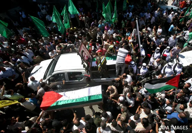 Relatives and masked Palestinian militants carry flag-drapped coffins containing the remains of Palestinian militants after the arrival of the caskets in Gaza City, 31 May 2012. Israel handed over the remains of dozens o...