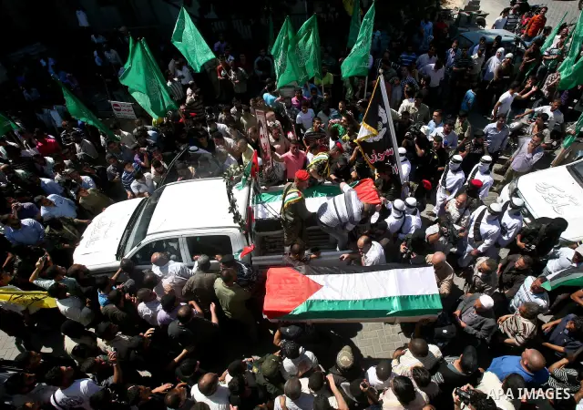 Relatives and masked Palestinian militants carry flag-drapped coffins containing the remains of Palestinian militants after the arrival of the caskets in Gaza City, 31 May 2012. Israel handed over the remains of dozens o...