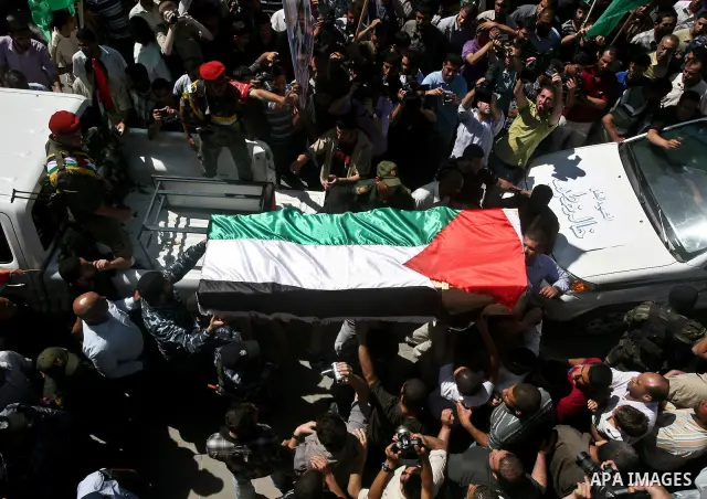 Relatives and masked Palestinian militants carry flag-drapped coffins containing the remains of Palestinian militants after the arrival of the caskets in Gaza City, 31 May 2012. Israel handed over the remains of dozens o...