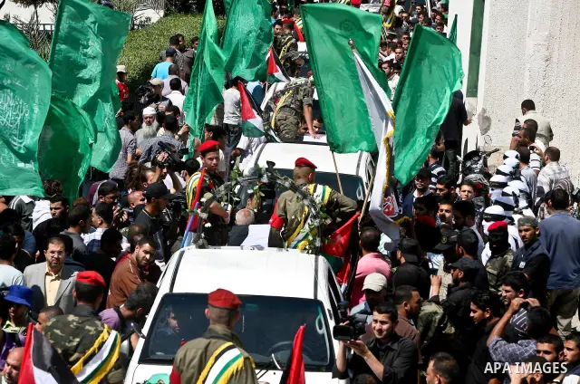 Relatives and masked Palestinian militants carry flag-drapped coffins containing the remains of Palestinian militants after the arrival of the caskets in Gaza City, 31 May 2012. Israel handed over the remains of dozens o...