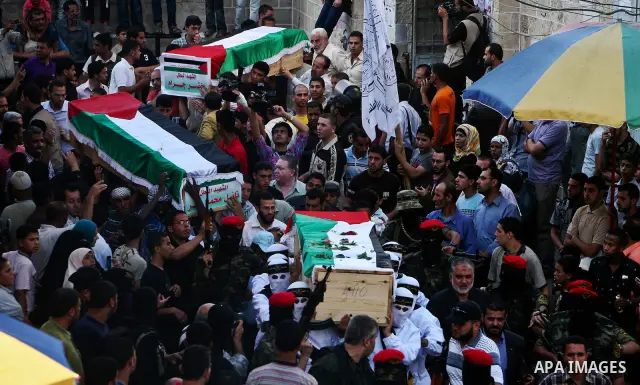 Relatives and masked Palestinian militants carry flag-drapped coffins containing the remains of Palestinian militants after the arrival of the caskets in Gaza City, 31 May 2012. Israel handed over the remains of dozens o...