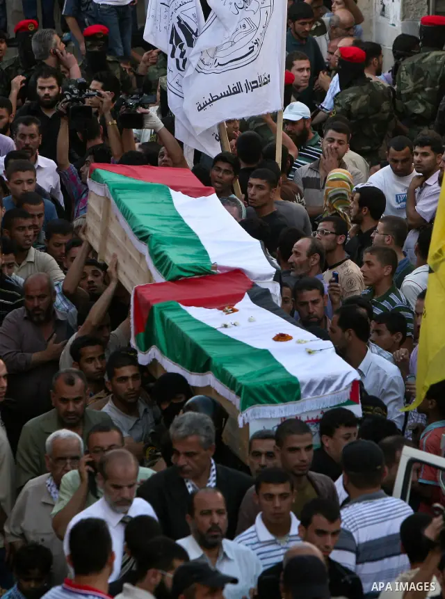Relatives and masked Palestinian militants carry flag-drapped coffins containing the remains of Palestinian militants after the arrival of the caskets in Gaza City, 31 May 2012. Israel handed over the remains of dozens o...