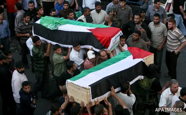 Relatives and masked Palestinian militants carry flag-drapped coffins containing the remains of Palestinian militants after the arrival of the caskets in Gaza City, 31 May 2012. Israel handed over the remains of dozens o...