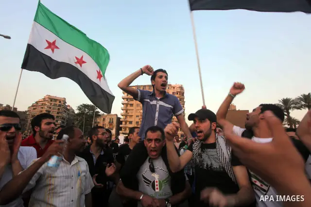 Syrians living in Egypt wave the revolutionary flag and shout slogans as they protest against the weekend massacre of Houla, in front of the Syrian embassy in Cairo, Egypt, 31 May 2012. A massacre was reported in the cen...