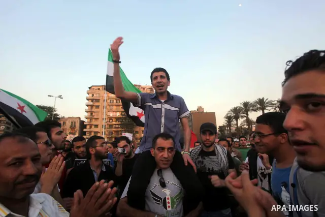 Syrians living in Egypt wave the revolutionary flag and shout slogans as they protest against the weekend massacre of Houla, in front of the Syrian embassy in Cairo, Egypt, 31 May 2012. A massacre was reported in the cen...