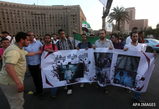 Syrians living in Egypt wave the revolutionary flag and shout slogans as they protest against the weekend massacre of Houla, in front of the Syrian embassy in Cairo, Egypt, 31 May 2012. A massacre was reported in the cen...