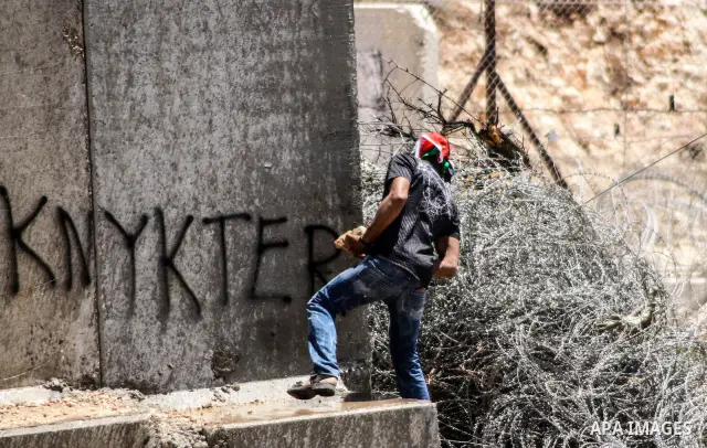 Palestinian protester hurls stones at Israeli soldiers during a weekly demonstration against Israel's controversial separation barrier in the West Bank village of Nilin on June 1, 2012. When completed, 85 percent of the...