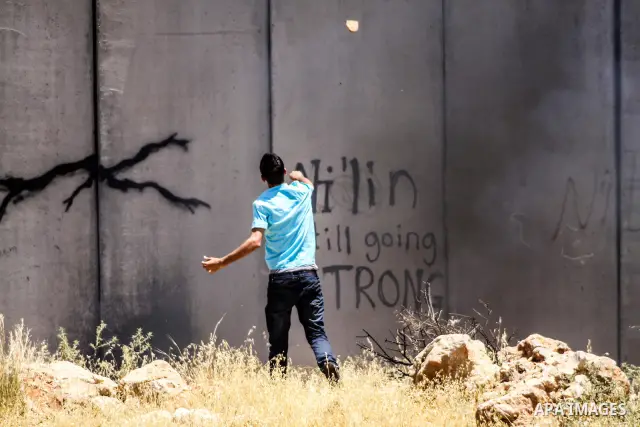 Palestinian protester hurls stones at Israeli soldiers during a weekly demonstration against Israel's controversial separation barrier in the West Bank village of Nilin on June 1, 2012. When completed, 85 percent of the...