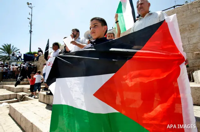 Palestinians hold national flag and shout slogans during a protest against continuing of 'Judaization of Jerusalem' by Jewish settlers and confiscating Palestinian lands at Al Tur and Damascus gate after Friday prayer in...