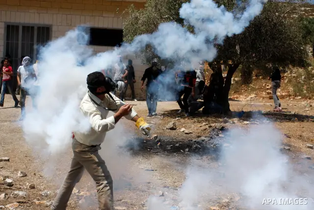 A Palestinian protester throws back a tear gas grenade towards Israeli soldiers during a demonstration against the expropriation of Palestinian land by Israel in the village of Kafr Qaddum, near the West Bank city of Nab...