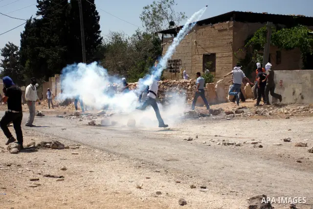 A Palestinian protester throws back a tear gas grenade towards Israeli soldiers during a demonstration against the expropriation of Palestinian land by Israel in the village of Kafr Qaddum, near the West Bank city of Nab...