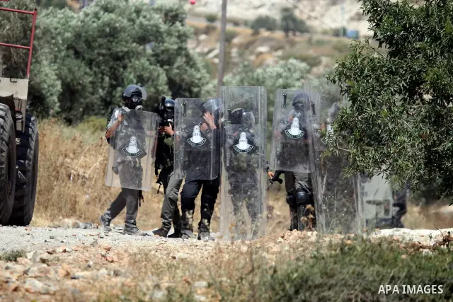 Israeli soldiers hold their protective shields as a comrade fires a tear gas canister at Palestinian protesters during a demonstration against the expropriation of Palestinian land by Israel in the village of Kafr Qaddum...