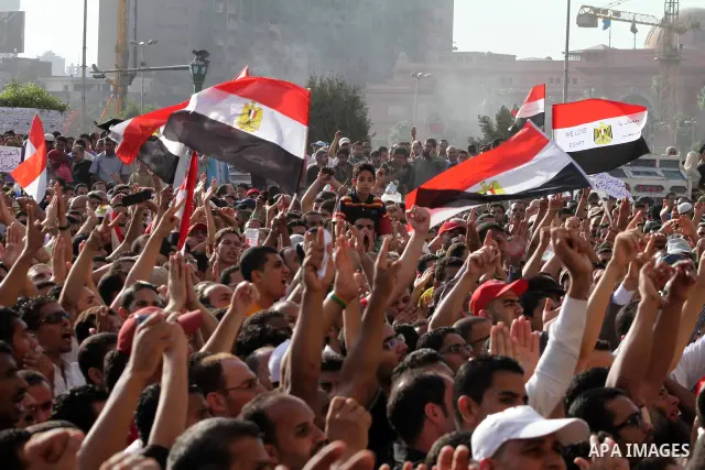 Egyptian protesters hold their national flag and effigies of the heads of former President Hosni Mubarak and his sons during a protest hours after the announcement of the verdict in their trial, in Tahrir square, Cairo,...