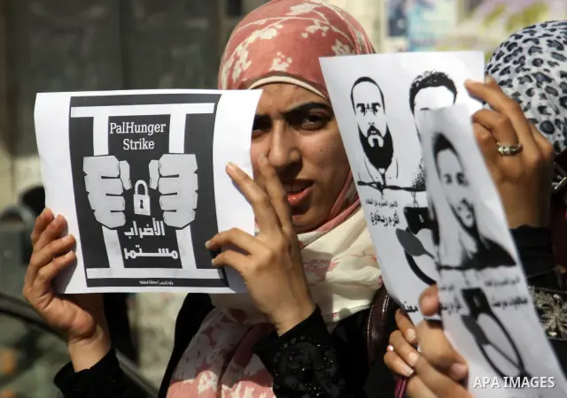 Palestinian protestors hold pictures of Palestinian prisoners Mahmoud al-Sarsak and Akram al-Rikhawi, whose are still refusing food for 80 days after a deal was made to end a mass prisoner hunger strike, during a demonst...