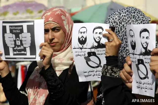 Palestinian protestors hold pictures of Palestinian prisoners Mahmoud al-Sarsak and Akram al-Rikhawi, whose are still refusing food for 80 days after a deal was made to end a mass prisoner hunger strike, during a demonst...
