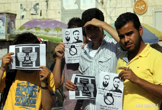 Palestinian protestors hold pictures of Palestinian prisoners Mahmoud al-Sarsak and Akram al-Rikhawi, whose are still refusing food for 80 days after a deal was made to end a mass prisoner hunger strike, during a demonst...