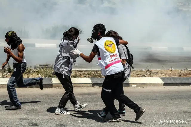 Palestinian protesters take cover from tear gas fired by Israeli soldiers during clashes at the entrance to Ofer prison, near the West Bank city of Ramallah, on June 5, 2012 following a demonstration to mark "Naksa Day",...