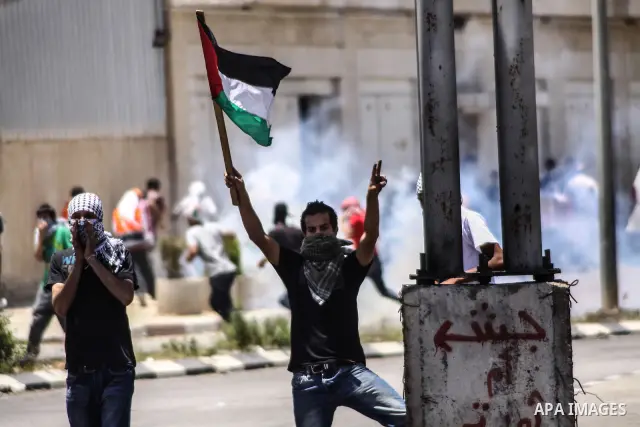 A Palestinian protester waves a national flag during clashes at the entrance to Ofer prison, near the West Bank city of Ramallah, on June 5, 2012 following a demonstration to mark "Naksa Day", the 44th anniversary of the...