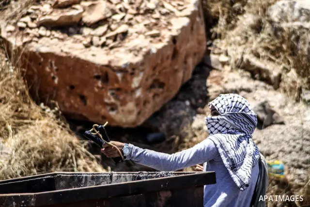 A Palestinian protester throws stones at Israeli soldiers during clashes at the entrance to Ofer prison, near the West Bank city of Ramallah, on June 5, 2012 following a demonstration to mark "Naksa Day", the 44th annive...