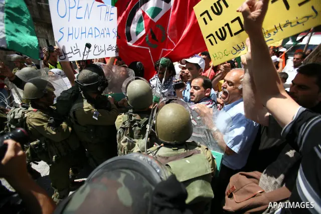 Palestinian protesters hold flags and banners during a demonstration against the Israeli occupation and to mark "Naksa Day", the 44th anniversary of the 1967 Six Day War, at the entrance of the old city near the settleme...