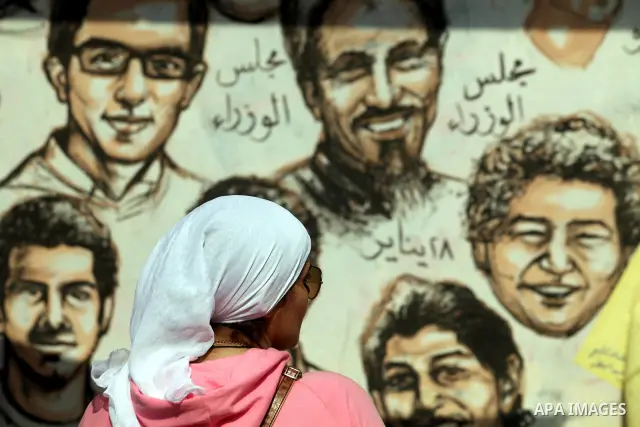 A woman walks in front of a wall filled with graffiti against the Supreme Council of the Armed Forces (SCAF) near Tahrir Square during a demonstration in Cairo June 5, 2012. Activists urged Egyptians to turn out for a bi...
