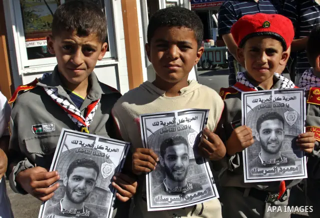 Palestinian protestors hold pictures of Palestinian prisoners Mahmoud al-Sarsak and Akram al-Rikhawi, whose are still refusing food for 80 days after a deal was made to end a mass prisoner hunger strike, during a demonst...