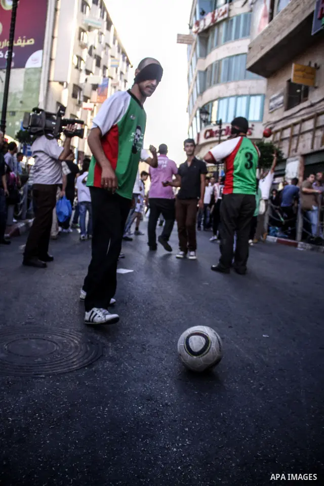 Palestinian youth play football in the streets of Ramallah during a rally solidarity with Palestinian prisoner Mahmoud Al-Sarsak who is still refusing food after a deal was made to end a mass prisoner hunger strike, on 0...