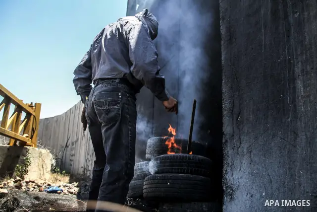 Palestinian protester burns tires during a weekly demonstration against Israel's controversial separation barrier in the West Bank village of Nilin on June 8, 2012. When completed, 85 percent of the wall will have been b...