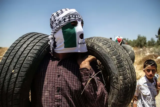 Palestinian protester burns tires during a weekly demonstration against Israel's controversial separation barrier in the West Bank village of Nilin on June 8, 2012. When completed, 85 percent of the wall will have been b...