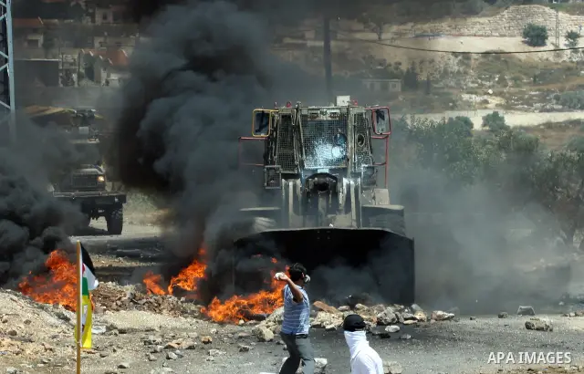 Palestinian protesters throw stones toward Israeli military bulldozer during clashes after a demonstration against the nearby Jewish settlement of Kdumim, in the West Bank village of Kfar Kadum, near Nablus June 8, 2012....